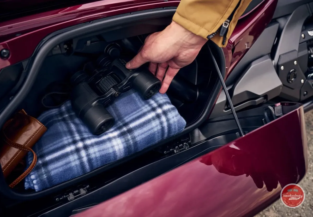 Rider opening the front storage compartment of a red Honda Gold Wing Tour, revealing packed luggage inside