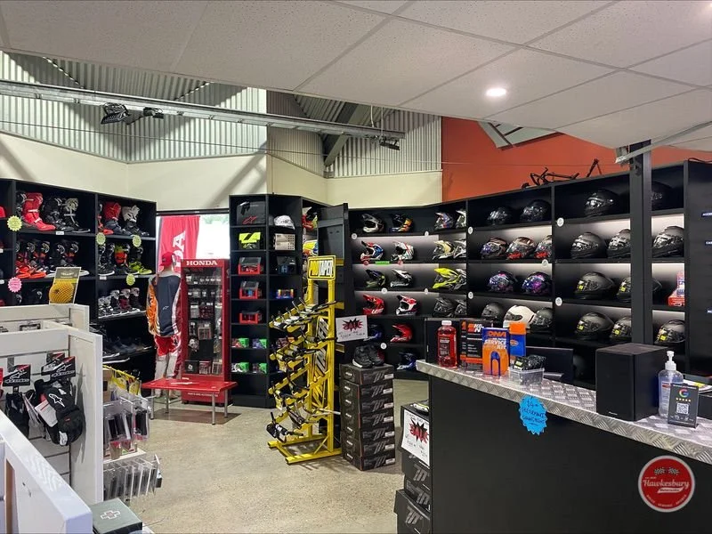 The helmet wall inside Hawkesbury Motorcycles — road and off-road helmets on shelves beside the accessories counter