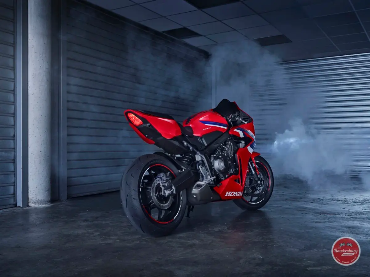 Red Honda CBR650R supersport motorcycle in a workshop with smoke drifting in the background